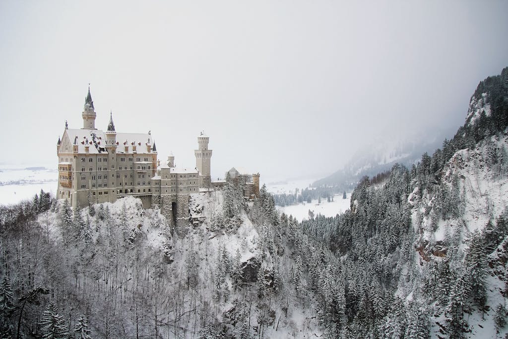 Majestic Neuschwanstein Castle surrounded by snowy Bavarian forest.